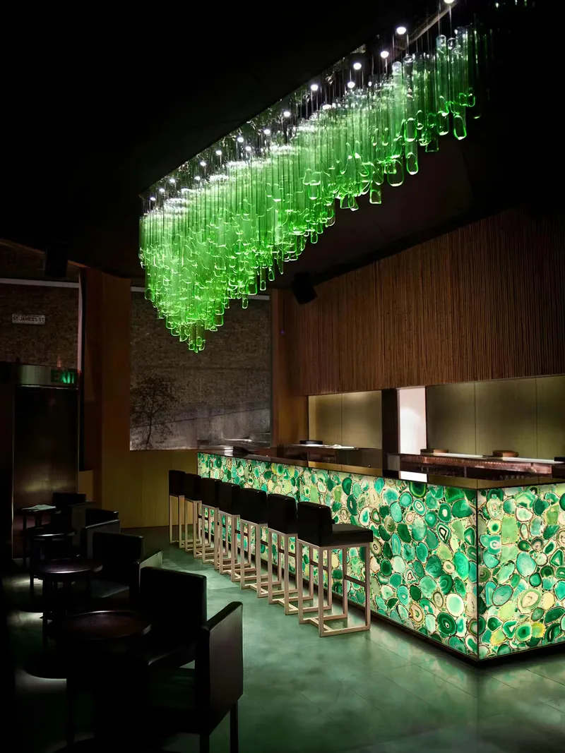 Comptoir de bar rétroéclairé en agate verte dans un intérieur sombre